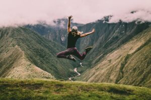 Stock image of a carefree person jumping into the air with beautiful scenery in the background.